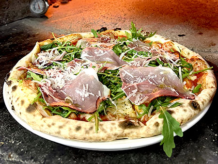 Pizza mit Parmaschninken im Steinofen mit Holzfeuer gebacken
